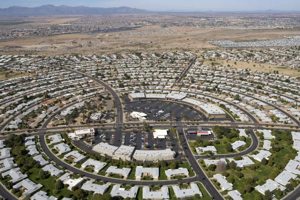 Aerial view of circular street pattern with buildings in Sun City, Arizona with desert mountains in background
